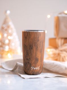 a wooden tumbler sitting on top of a table next to wrapped presents and candles