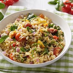 a white bowl filled with pasta salad on top of a green and white checkered table cloth