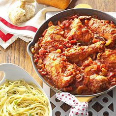 a pan filled with pasta and meat next to other food items on a wooden table