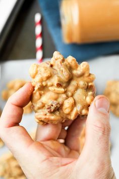 a hand holding up a cookie with nuts on it