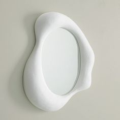 a white mirror mounted to the side of a wall next to a light gray wall