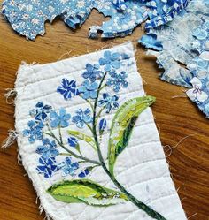 some blue flowers and leaves are on a piece of fabric that has been stitched together