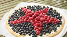 a pizza topped with berries and blueberries in the shape of a heart on top of a napkin