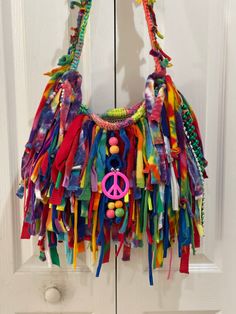 a multicolored purse hanging on the front door with beads and peace sign decoration