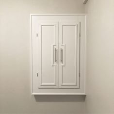 a white cabinet with two doors on the wall