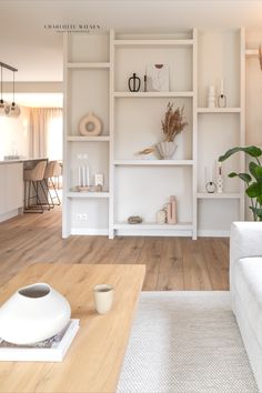 a living room filled with lots of white furniture and shelves full of vases on top of them