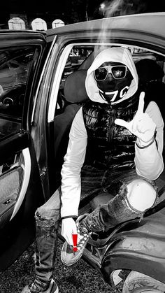 a man in a gas mask is sitting in the back of a car with his hand up