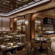 a restaurant with many tables and chairs in front of a bar filled with lit candles