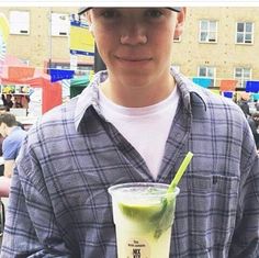 a young man holding a drink in his hand