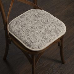 a wooden chair with a white fabric seat pad on top of it, sitting on a hard wood floor