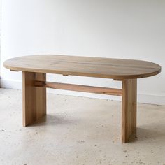 a wooden table sitting on top of a floor next to a white wall in a room