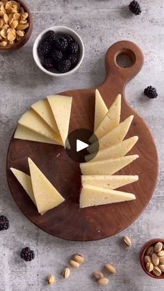 cheese and nuts on a cutting board next to a bowl of raisins, jam