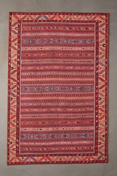 a red and blue rug with many different patterns on the ground, including one in the middle