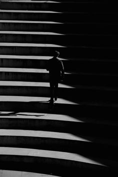 a man walking up some steps in the dark with his shadow on the wall behind him