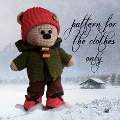 a crocheted teddy bear wearing a red hat and green jacket in the snow