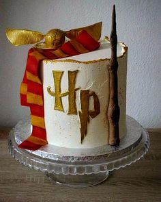 a harry potter themed birthday cake on a glass platter with a wand and scroll