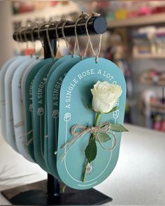 four tags hang on a rack with a white rose