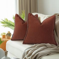 two red pillows on a white couch in a living room