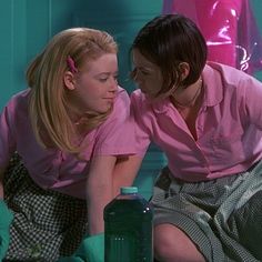 two young women in pink shirts and plaid skirts are looking at each other's eyes