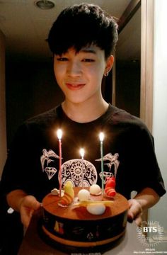 a boy holding a birthday cake with lit candles