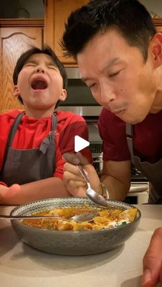 a man and boy are eating food in the kitchen