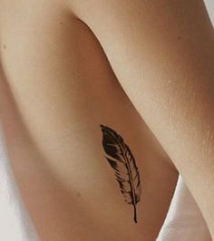 a woman's arm with a tattoo on it that has a black feather in it