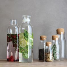 bottles filled with different types of herbs and spices on top of a wooden table next to each other