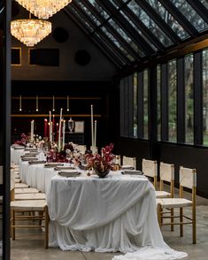 a long table is set with white linens and candles