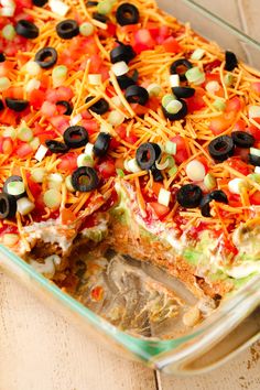 a casserole dish filled with vegetables, cheese and black olives is ready to be eaten