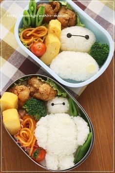 two bento boxes filled with food on top of a wooden table next to each other