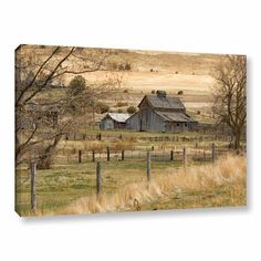 an old barn sits in the middle of a field with trees and grass on either side