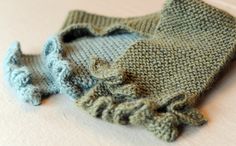 a knitted mitten laying on top of a white table next to a pair of gloves