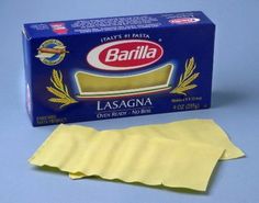 an unopened box of lasagna on a blue surface with a yellow napkin