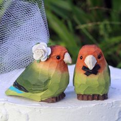 two colorful birds sitting on top of a cake