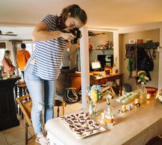 a woman standing on top of a table holding a camera next to a plate of food