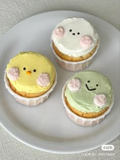 three decorated cupcakes sitting on top of a white plate