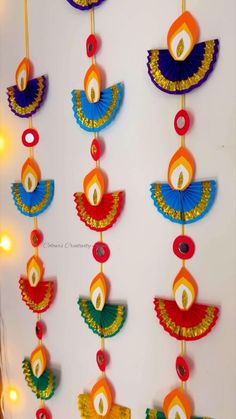 an assortment of colorful paper decorations hanging on a wall with lights in the back ground