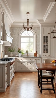 a large kitchen with white cabinets and wood flooring on the walls, along with a wooden dining table surrounded by chairs