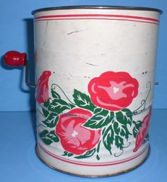 an old tin can with flowers painted on it's sides and red handles, sitting on a blue surface