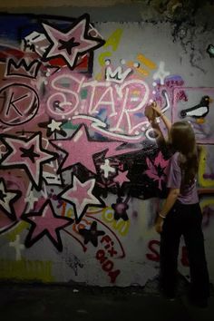 a woman is painting graffiti on a wall