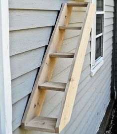 a set of stairs made out of wood sitting on the side of a house next to a window