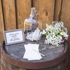 a wooden barrel with flowers on it next to a sign