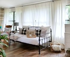 a living room filled with lots of furniture next to a white window covered in curtains