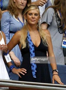 a woman in a black dress and blue tie at a tennis match