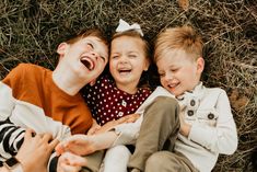 three young children laying on the ground laughing and having fun with their hands around each other