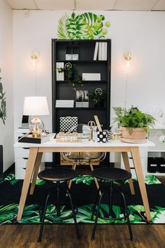 a table with two chairs in front of it and plants on the wall behind it