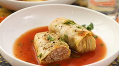 two white bowls filled with soup and some meat wrapped in tortilla wrappers