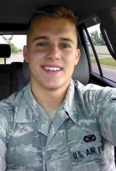 a man in uniform sitting in the back seat of a car with his hand up