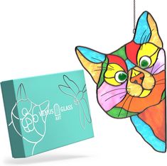 a colorful cat ornament next to a blue box with the logo jesus glass art