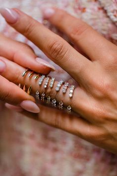 a woman's hand with five rings on her fingers and one ring in the middle